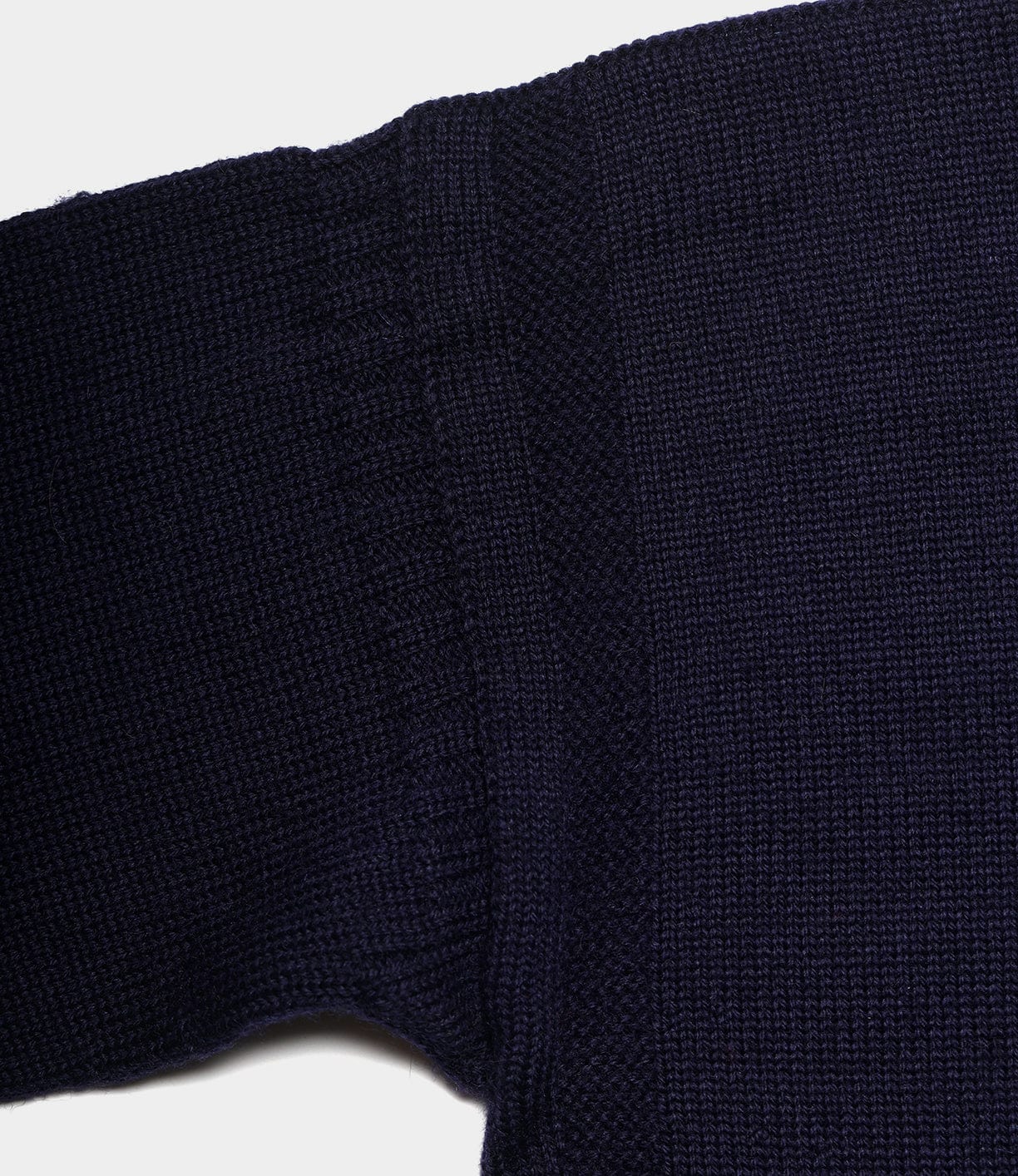 Close-up of a navy blue Guernsey Sweater by Best Made Co., highlighting textured stitching and ribbed cuffs, with traditional seamless knitting shown against a white background.