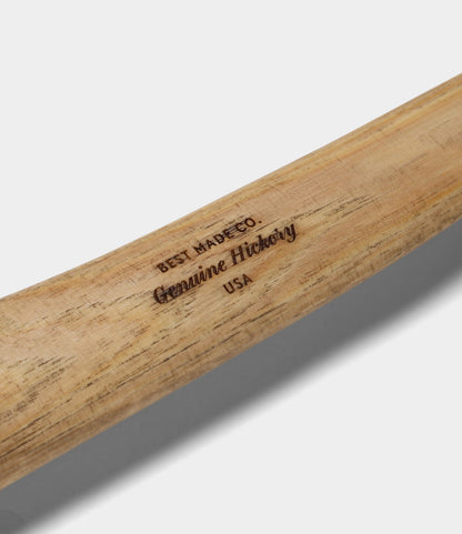 A close-up of The Phantom's wooden handle by Best Made Co., stamped “Genuine Hickory USA,” reveals the natural wood grain and smooth finish—expertly crafted to complement a hand-forged felling axe.