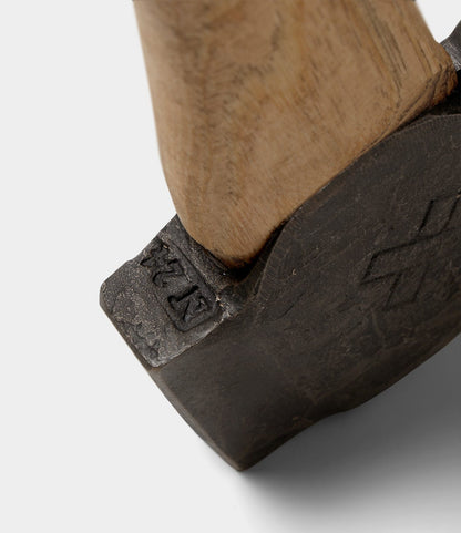 Close-up of The Phantom hammer by Best Made Co., featuring a dark, textured metal head with "NZ" stamped on the side, hand-forged style, and mounted on a wooden handle against a plain light gray background.