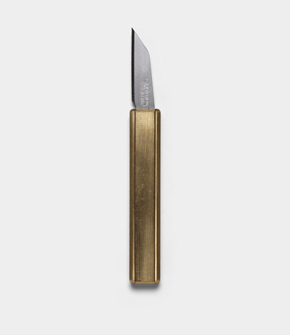 The Best Made Co. Studio Knife, with its rectangular metallic gold handle and sharp angled silver blade, is displayed against a plain white background.