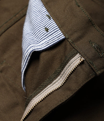 Close-up of Best Made Co.'s Standard 5-Pocket Pant in Deep Olive, featuring a visible brass zipper, blue and white striped lining, textured canvas fabric, and detailed 5-pocket stitching.