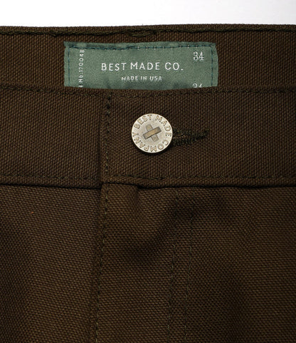 Close-up of Standard 5-Pocket Pant Deep Olive by Best Made Co., featuring a silver button engraved with the brand and a green inner label that reads Best Made Co., Made in USA, 34.