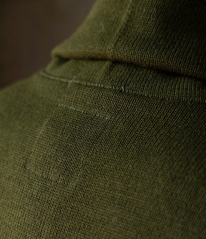 Close-up of the Dehen Shawl Neck Sweater in Moss Green by Best Made Co., featuring a visible rectangular patch repair that showcases the textured worsted wool and fine details inspired by classic American workwear.