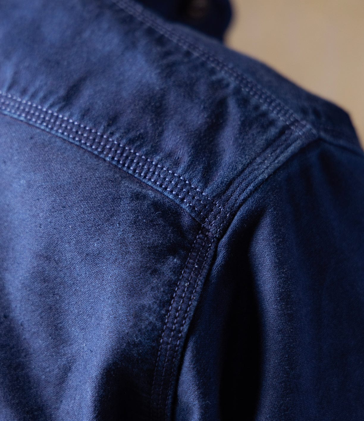 Close-up of the Best Made Co Indigo Moleskin Work Shirt, showcasing the shoulder seam and fine stitching under soft light that accentuates the fabric's rich texture.