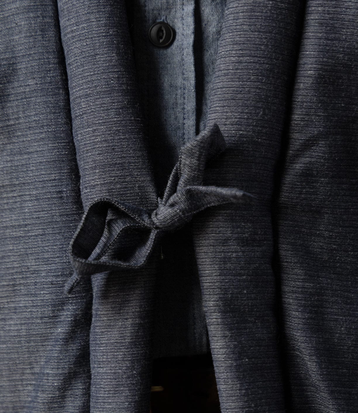 Close-up of the Best Made Co. Quilted Hanten Jacket in dark blue with a tied belt at the front, worn over a buttoned shirt—showcasing classic Japanese workwear style.