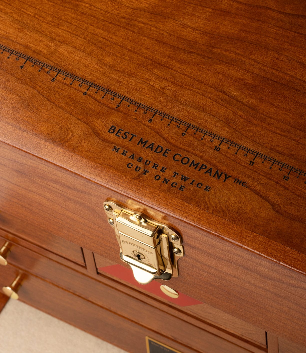 A close-up of the Gerstner 41D Founder’s Edition tool chest by Best Made Co., featuring polished American cherry, brass hardware, a built-in top ruler, and “BEST MADE COMPANY INC. MEASURE TWICE CUT ONCE” engraved on the lid.