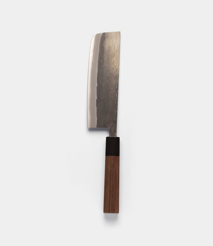 The Best Made Co. Aogami Nakiri Knife, crafted from Blue Paper Steel No. 2, features a flat-edged, dark-textured steel blade and a cylindrical wooden handle with a dark bolster, presented vertically against a plain light gray background.