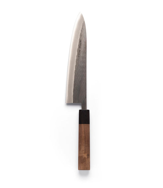 A vertical studio shot of the Aogami Gyuto Knife by Best Made Co. against a plain white background. This gyuto knife showcases a polished, dark-textured blade—expertly forged from Blue Paper Steel No. 2—and features a two-toned wooden handle.