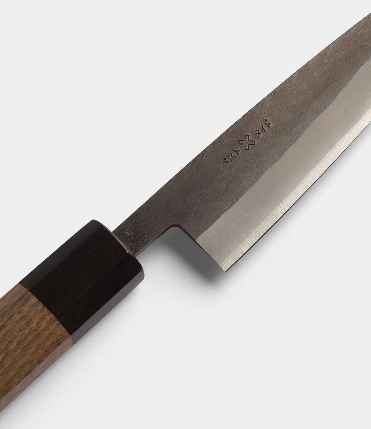 A close-up of the Best Made Co. Aogami Petty Knife, crafted with Blue Paper Steel No. 2 in a traditional san-mai construction, featuring a wooden handle and engraved characters on the blade, set against a plain light gray background.
