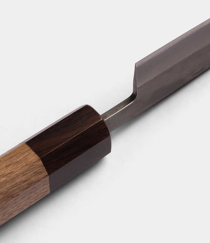 Close-up of the Best Made Co. Aogami Petty Knife, featuring a two-tone wooden handle and a partially visible san-mai Blue Paper Steel No. 2 blade, set against a white background.