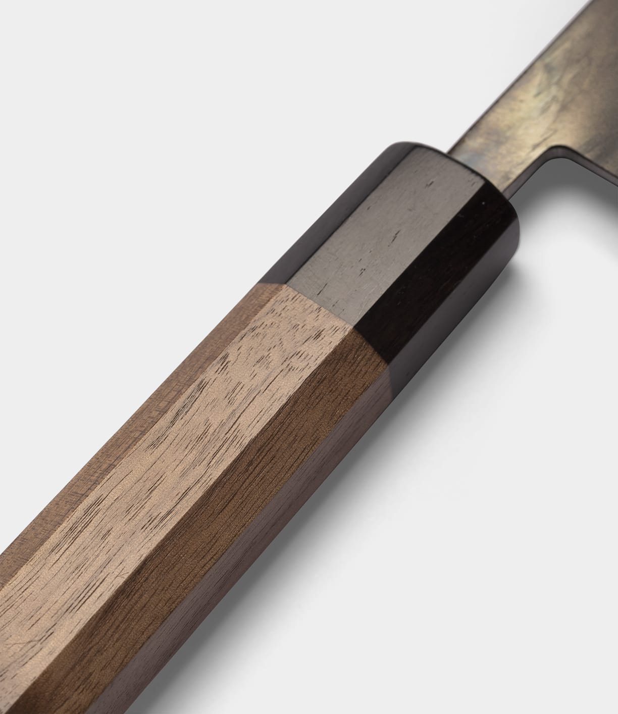 Close-up of the wooden handle of the Best Made Co. Aogami Gyuto Knife, featuring a dark bolster and highlighting the smooth texture and natural grain of the wood against a plain, light background. This elegant handle is designed for both comfort and precision, reflecting the quality craftsmanship of this Japanese chef knife.