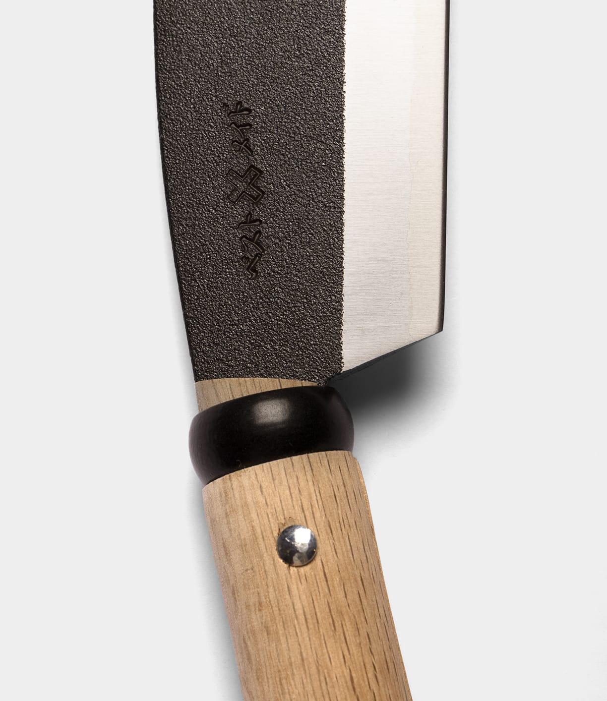 Close-up of a Best Made Co. Sayanata Hatchet with a wooden handle, black bolster, and a partially textured Nippon carbon steel blade featuring engraved markings near the base.