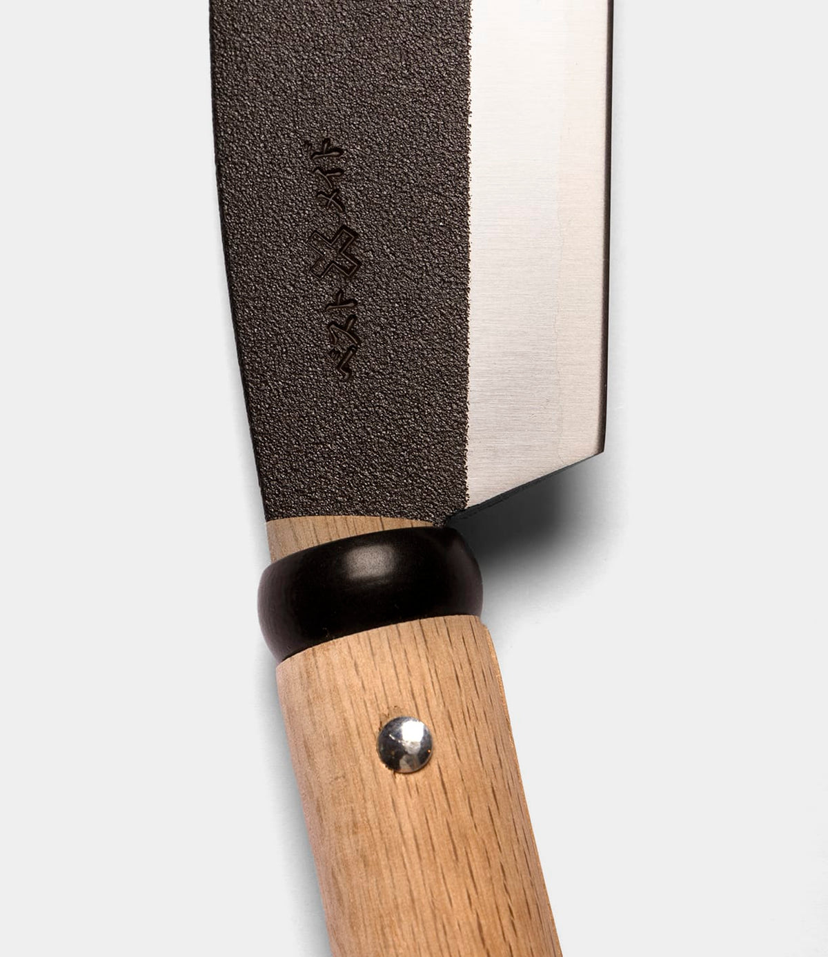 Close-up of a Best Made Co. Sayanata Hatchet with a wooden handle, black bolster, and a partially textured Nippon carbon steel blade featuring engraved markings near the base.