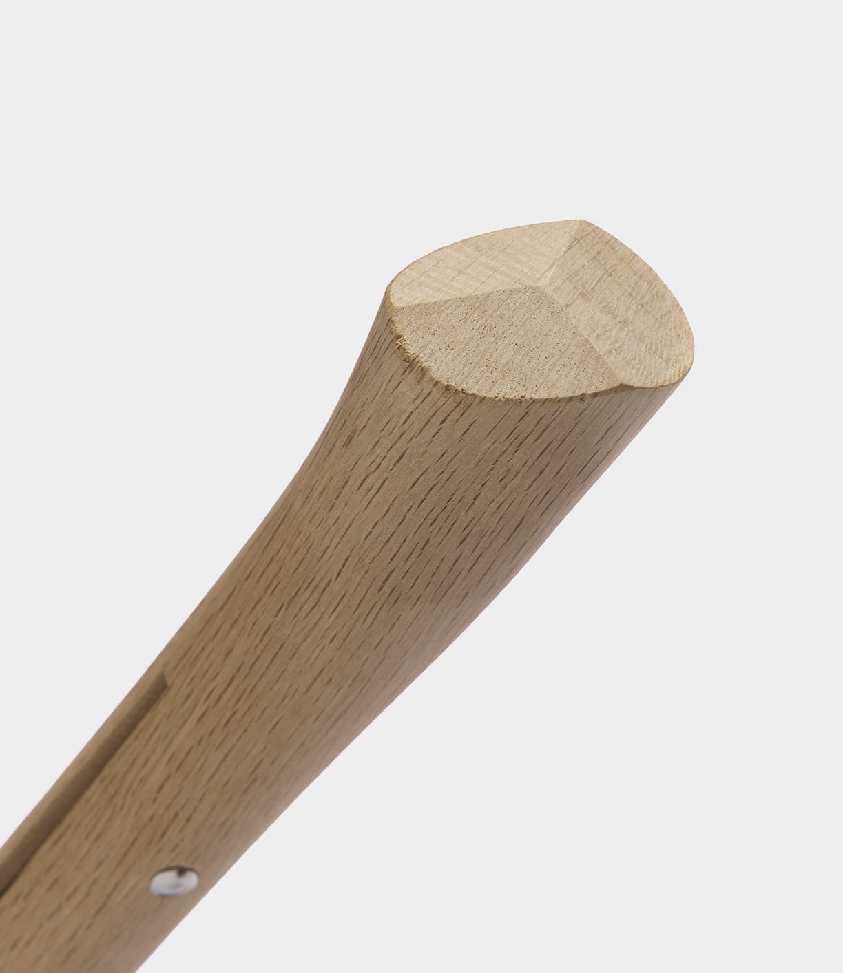 Close-up of a smooth, light wooden handle with a rounded triangular end, set against a plain white background. The Best Made Co. Sayanata Hatchet features a versatile blade crafted from premium Nippon carbon steel.