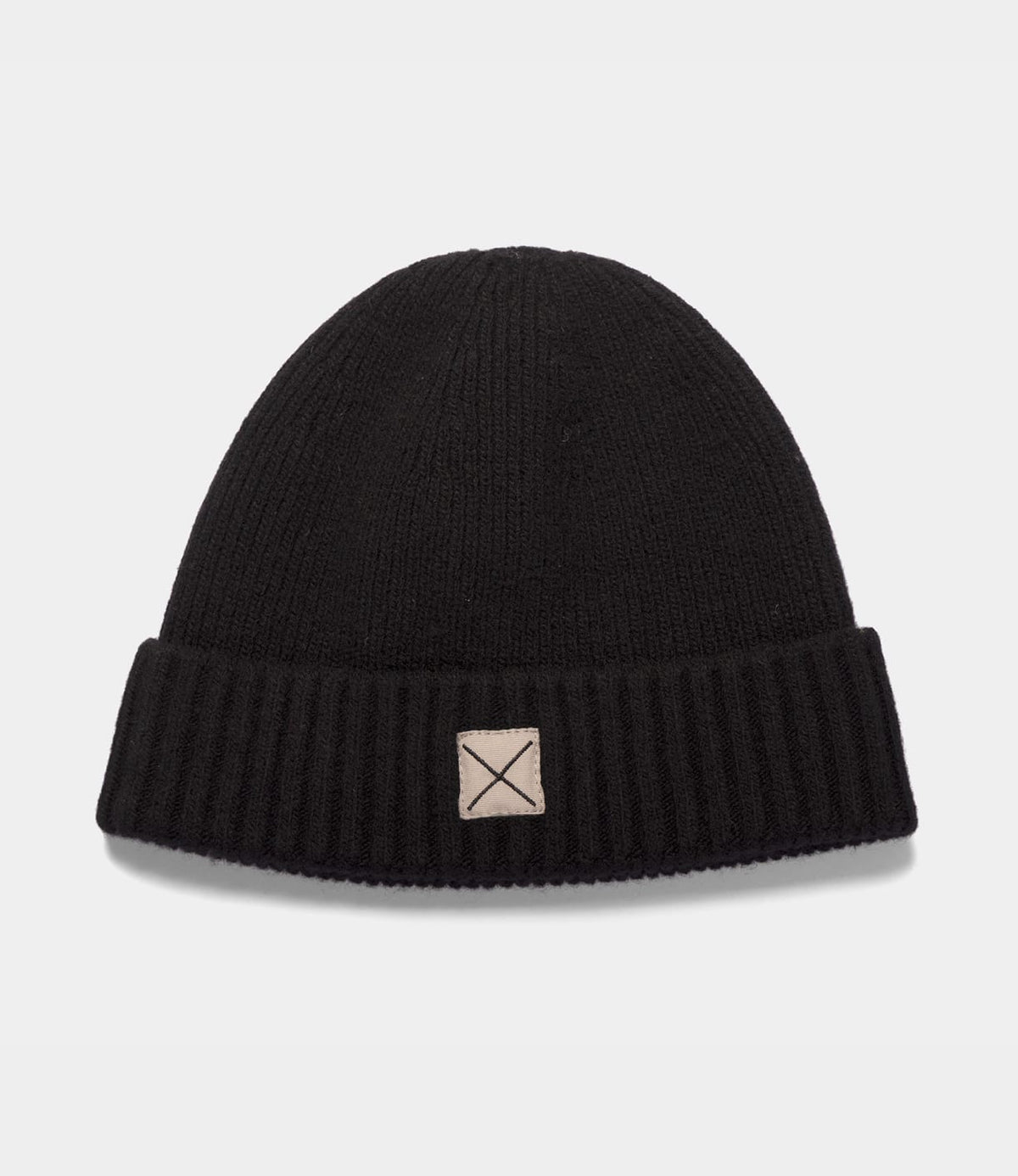 Black ribbed lambswool Cap of Courage beanie with a folded cuff and a square patch featuring an X stitch.