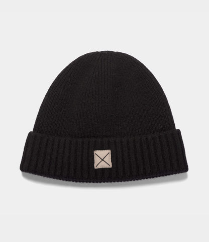 Black ribbed lambswool Cap of Courage beanie with a folded cuff and a square patch featuring an X stitch.