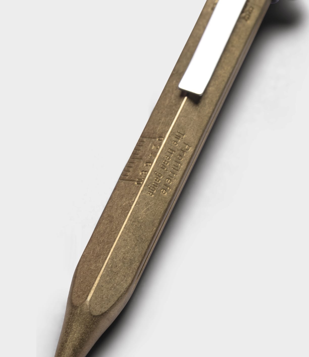 Close-up of the Best Made Co. Brass Messograf Pen, featuring a metallic gold-colored brass body, silver clip, and engraved text, set against a plain light gray background.