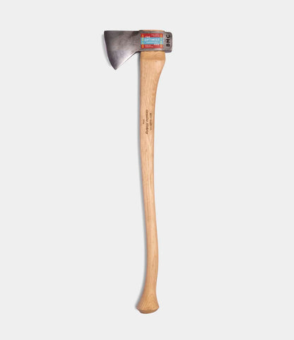 The Optimist by Best Made Co. is a single-bladed Hudson Bay axe featuring a 5160 carbon steel head and a long, curved wooden handle, shown on a plain white background with a label attached near the top of the metal head.