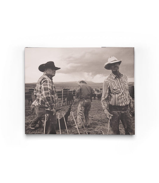 Three cowboys in hats and plaid shirts stand on a ranch with cattle behind them in this black-and-white image from Open Range by Best Made Co., evoking the timeless, vintage style of classic photography books.