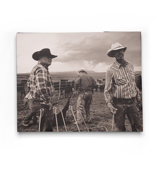 Three cowboys in hats and plaid shirts stand on a ranch with cattle behind them in this black-and-white image from Open Range by Best Made Co., evoking the timeless, vintage style of classic photography books.
