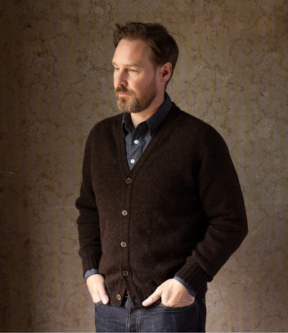 A man wearing a black Best Made Co. Black Sheep Cardigan over a blue collared shirt.
