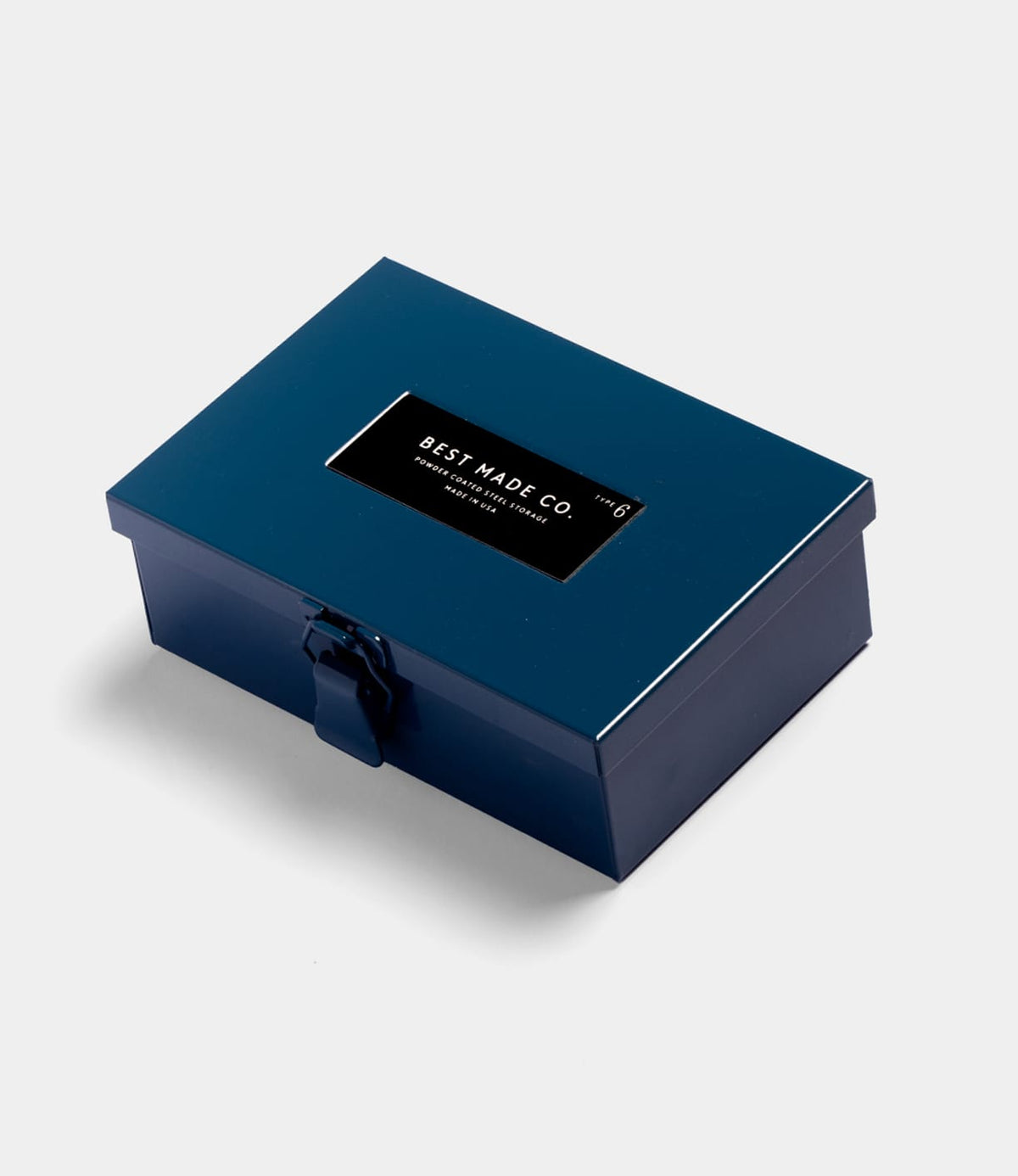The Type 6 Strongbox Blue by Best Made Co. is a rectangular, glossy navy steel box with a black clasp and lid label, ideal for secure storage.