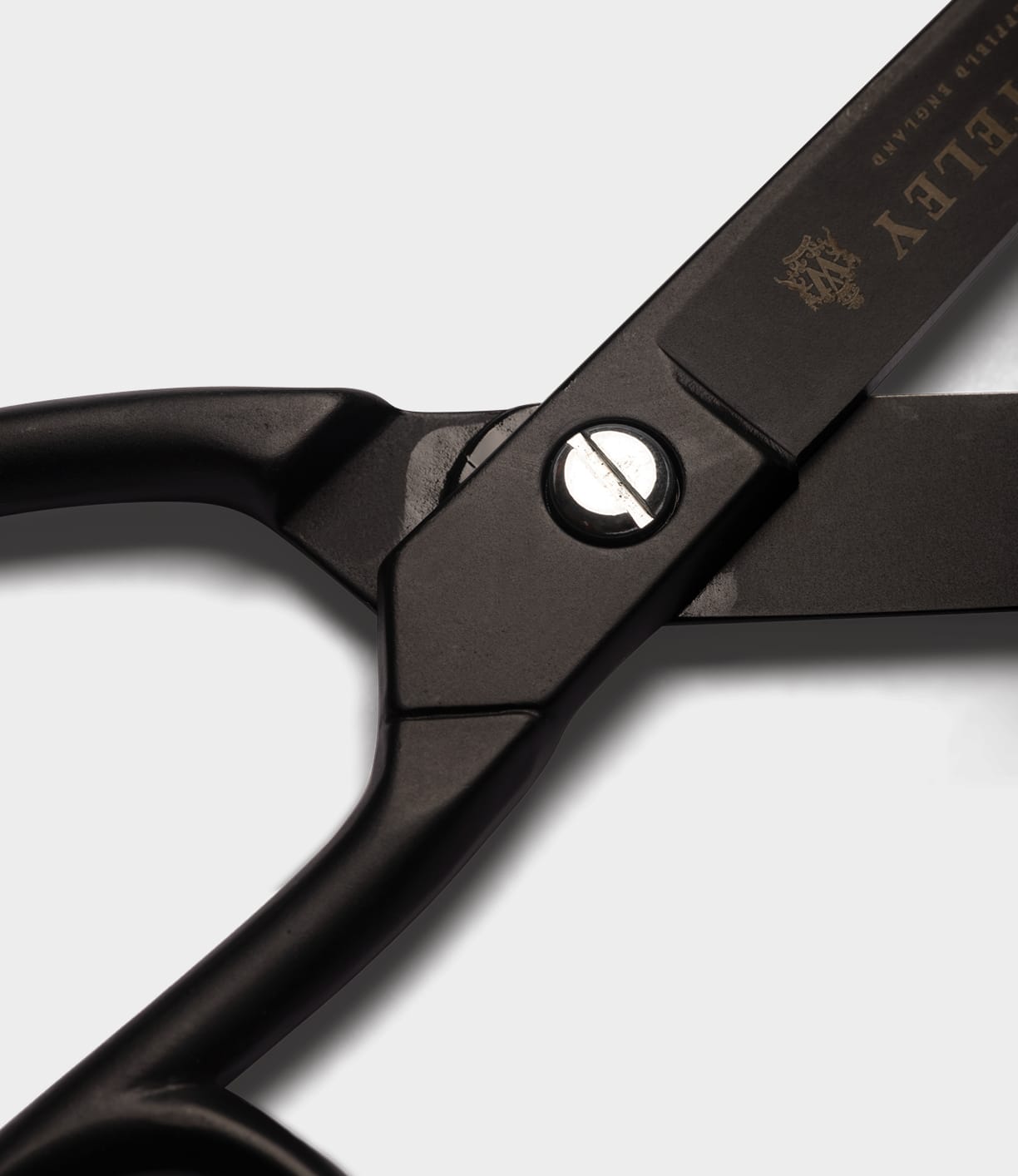 Close-up of Best Made Co. Ten-Inch Paper Scissors in black metal, crafted from hot-forged carbon steel with a visible pivot screw and part of the blade showing gold branding and text.