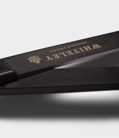 Close-up of Best Made Co. Ten-Inch Paper Scissors with black handles and gold branding on the blade, crafted from hot-forged carbon steel, set against a plain light gray background.