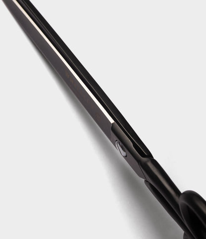 Close-up view of the black blade and handle of Best Made Co. Ten-Inch Paper Scissors, crafted from hot-forged carbon steel, photographed from an angle against a white background.