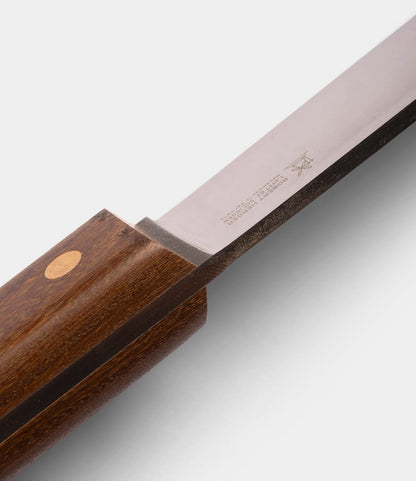 Close-up of the Best Made Co. Sailor’s Knife, featuring a Brazilian Teak handle and a polished Niolox steel blade with engraved text and symbols near the handle.