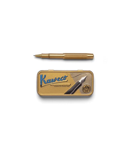 A Kaweco Sport brass pocket pen by Best Made Co., with its hexagonal cap off, rests beside a metal ruler showing precise centimeter and millimeter markings on a wooden surface. The pen is compatible with a G2 rollerball refill.