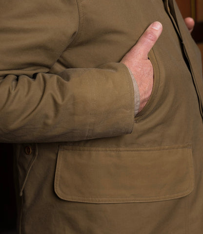 A man with his hand in his pocket wears the Best Made Co. Wool-Lined Waxed Field Jacket in Tan.