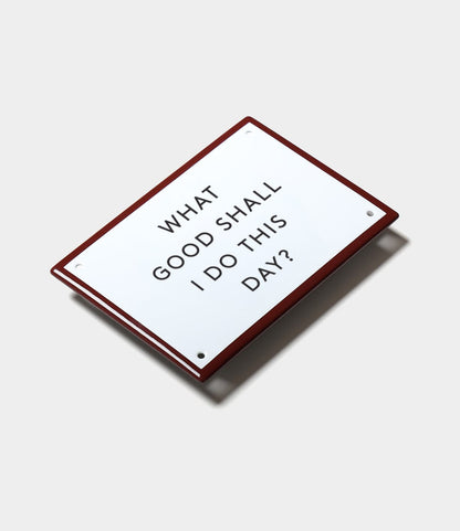 The “What Good” Enamel Steel Sign by Best Made Co. features a red border, white center, and black text: WHAT GOOD SHALL I DO THIS DAY?—an inspirational Benjamin Franklin-inspired décor piece.