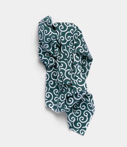 The Karakusa Tenugui by Best Made Co. is a dark green, hand-dyed Japanese cloth featuring a white swirling pattern created with the chusen technique, shown crumpled on a plain light background.