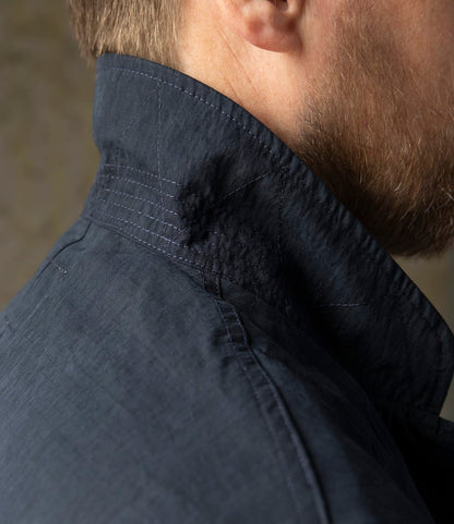 Close-up of a man's neck and jaw with a short beard, wearing the Best Made Co. Possibilities Jacket Navy—crafted from durable cotton Cordura with detailed stitching and textured fabric near the collar for versatile lightweight style.
