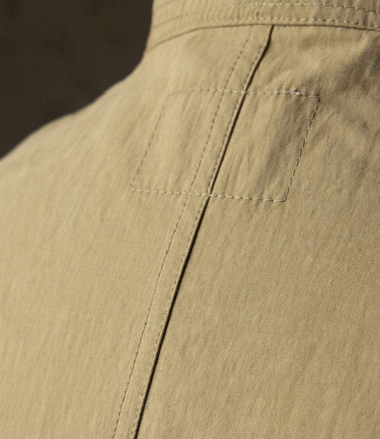 Close-up of the Possibilities Jacket Tan by Best Made Co., showcasing visible stitching, a vertical seam, and textured Japanese cotton fabric that highlight the craftsmanship and durability of this lightweight outerwear.