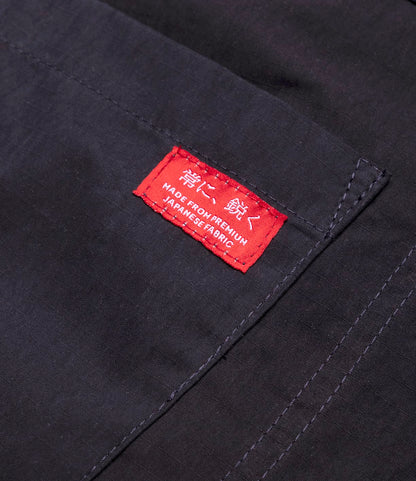 Close-up of navy ripstop fabric with stitched seams and a red label featuring Japanese characters and "MADE FROM PREMIUM JAPANESE FABRIC," on the lightweight Possibilities Jacket Navy by Best Made Co.