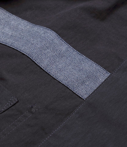 Close-up of dark navy fabric on the Best Made Co. Possibilities Jacket, highlighting a sewn-on light gray herringbone-patterned strip and detailed stitching.