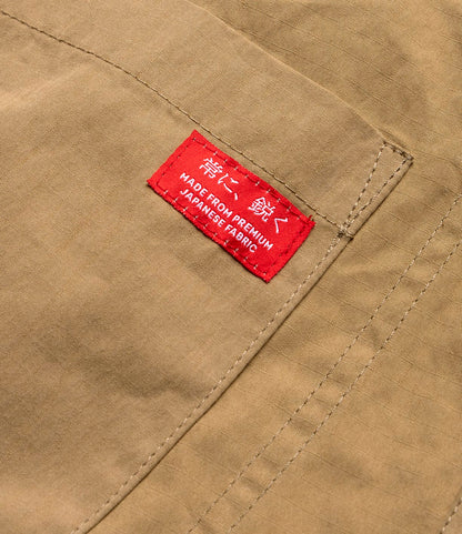 Close-up of tan fabric with visible stitching and a red label reading "MADE FROM PREMIUM JAPANESE FABRIC"—showing the quality detailing on the Best Made Co. Possibilities Jacket Tan, crafted for durable lightweight outerwear.
