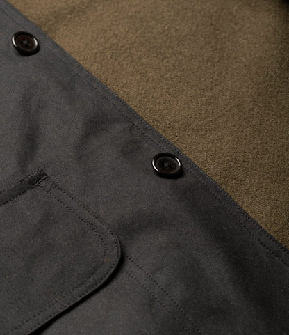 Close-up of Best Made Co.'s Wool-Lined Waxed Field Jacket Black, featuring dark buttons, olive green wool lining, and a black canvas pocket with visible stitching—a functional yet stylish outerwear piece.