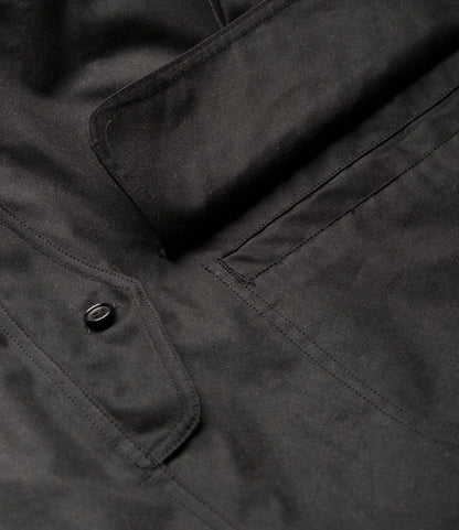 Close-up of the Best Made Co. Wool-Lined Waxed Field Jacket Black, showing a flap pocket with stitched outline and a single black button. The British Millerain Staywax material's texture and detailed stitching are clearly visible.