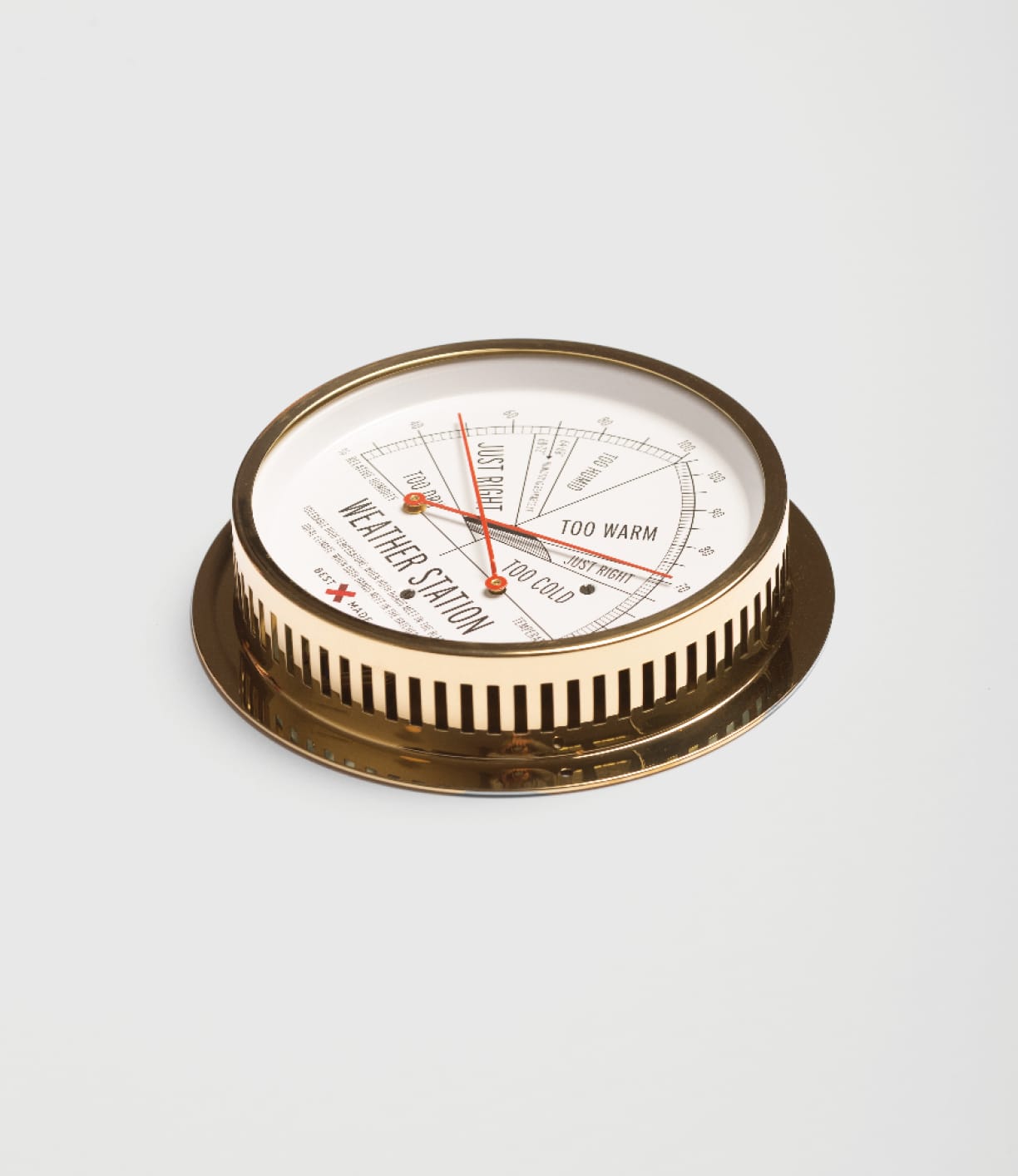 The Best Made Co. Weather Station is a round, vintage-style thermometer and hygrometer with a brass case and white dial; set on a white surface, its needle indicates the TOO WARM section for temperature and comfort levels.