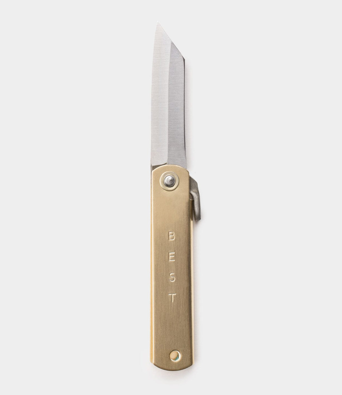 The Mid Brass Higo Knife by Best Made Co. features a straight-edged blade and a brass handle engraved vertically with "BEST." It is shown against a plain, light gray background.