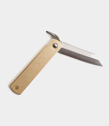 The Best Made Co. Mid Brass Higo Knife, with a straight steel blade and engraved brass handle, is partially open against a plain light background.