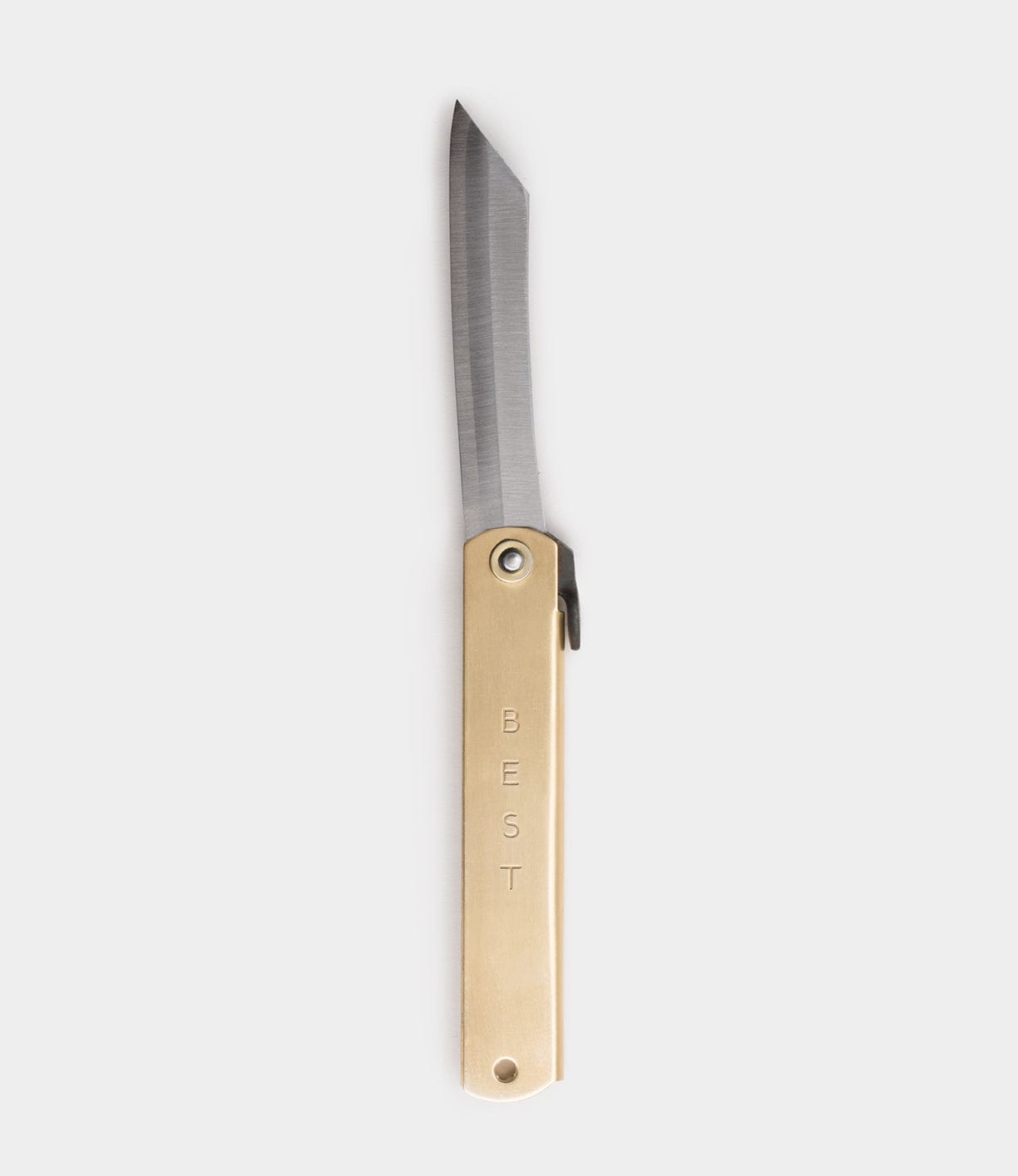 The Max Brass Higo Knife by Best Made Co is a Japanese folding knife with a straight-edged, pointed blade extended. Its brass handle features "BEST" engraved vertically. Shown on a plain, light gray background.