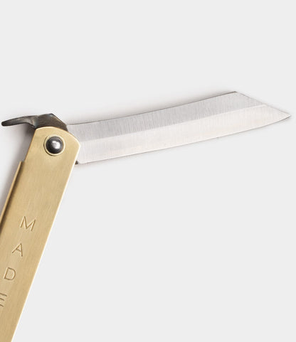 The Best Made Co. Max Brass Higo Knife, featuring a straight-edged, partially open steel blade, is photographed against a plain light gray background.