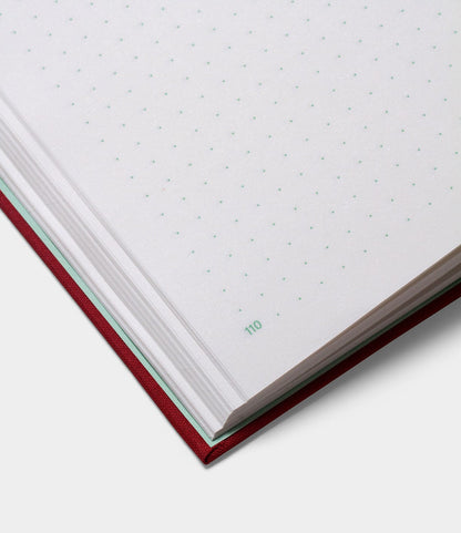 The S.B.T. Mid Cloth-Bound Notebook by Best Made Co. is open, showing dotted grid pages with a red hardcover. Page number 110 appears in green at the bottom corner, set against a plain white background.