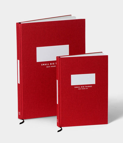 Two S.B.T. Mid Cloth-Bound Notebooks by Best Made Co. with red covers, in two sizes, stand upright on a white background. Each features white rectangular blocks and text, plus numbered pages on the front.