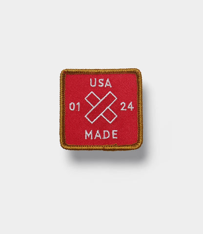 A square red fabric patch with a gold border, featuring "Old Gold No. 1" and "Best Made Co." in white, plus two crossed white bandages—an emblem inspired by Best Made Co.'s craftsmanship.