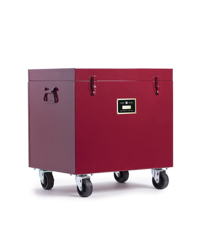 A spacious, deep red Rolling Footlocker from Best Made Company Archive, this storage trunk is made of heavy-duty 22-gauge steel and features robust handles, secure metal latches, a front label, and four caster wheels for easy mobility.